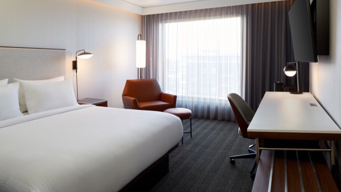 Chambre avec lit king, fauteuil et espace de travail au Courtyard par Marriott Montréal Midtown